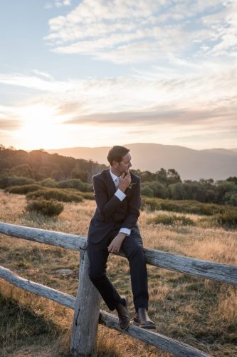 groom sat on a fence at sunset in Australia. 